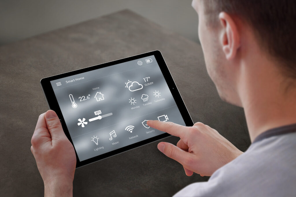 Man use application for smart home control on tablet. Interior of living room in the background.